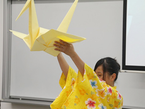 大きな折り鶴を見せる学生