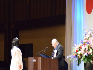 近藤雅彦JESC室長から表彰されるNCA総合デザイン科の村田恭奈さん。アメリカのアニメ映画「プロモーションツール制作」が高い評価を受けました。